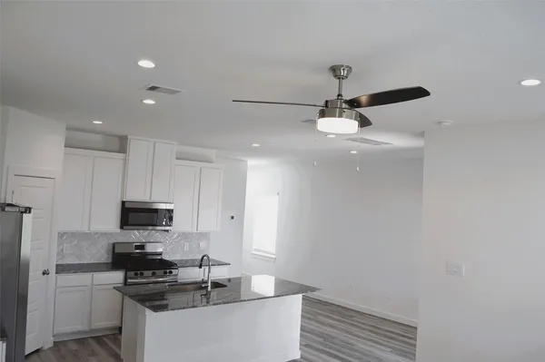 a kitchen with granite countertop a sink stainless steel appliances and cabinets