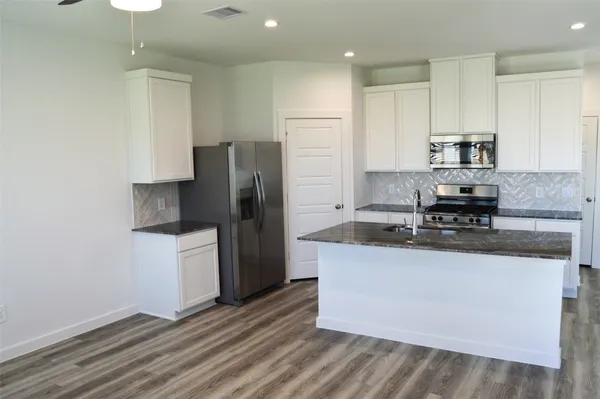 a kitchen with stainless steel appliances granite countertop a refrigerator a stove a sink and a microwave