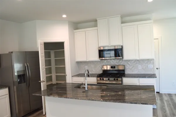 a kitchen with granite countertop a refrigerator a stove and a sink
