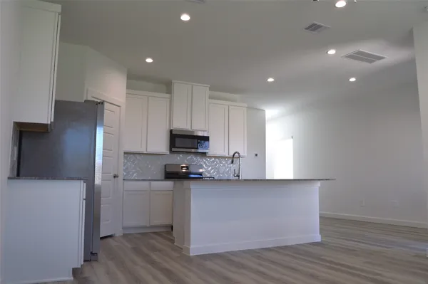 a kitchen with stainless steel appliances a sink a stove a refrigerator and cabinets