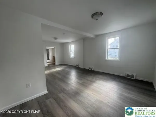 an empty room with wooden floor and windows