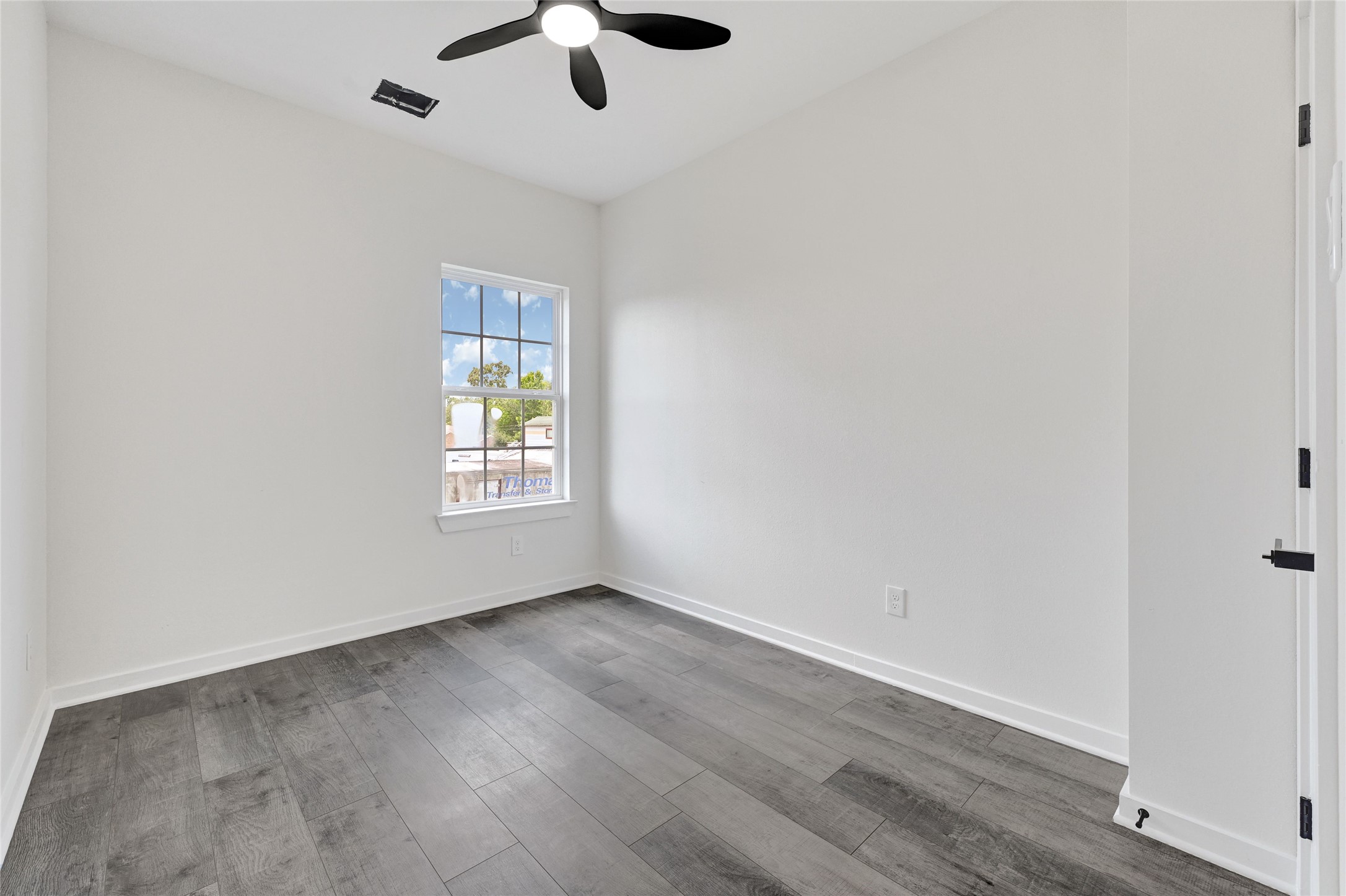 7922 Sealey Street Houston, TX 77088 - Photo 12 of 16 an empty room with wooden floor chandelier fan and windows
