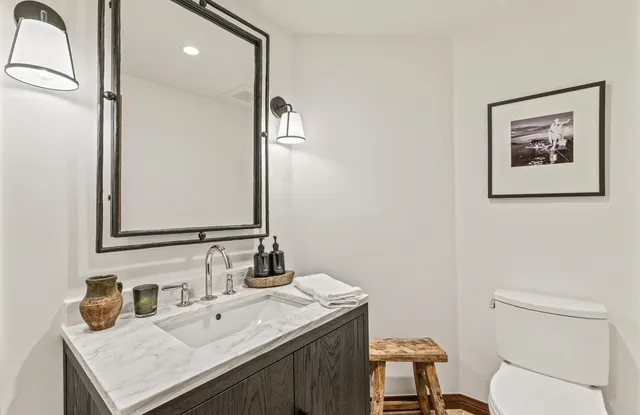 a bathroom with a granite countertop toilet sink and mirror