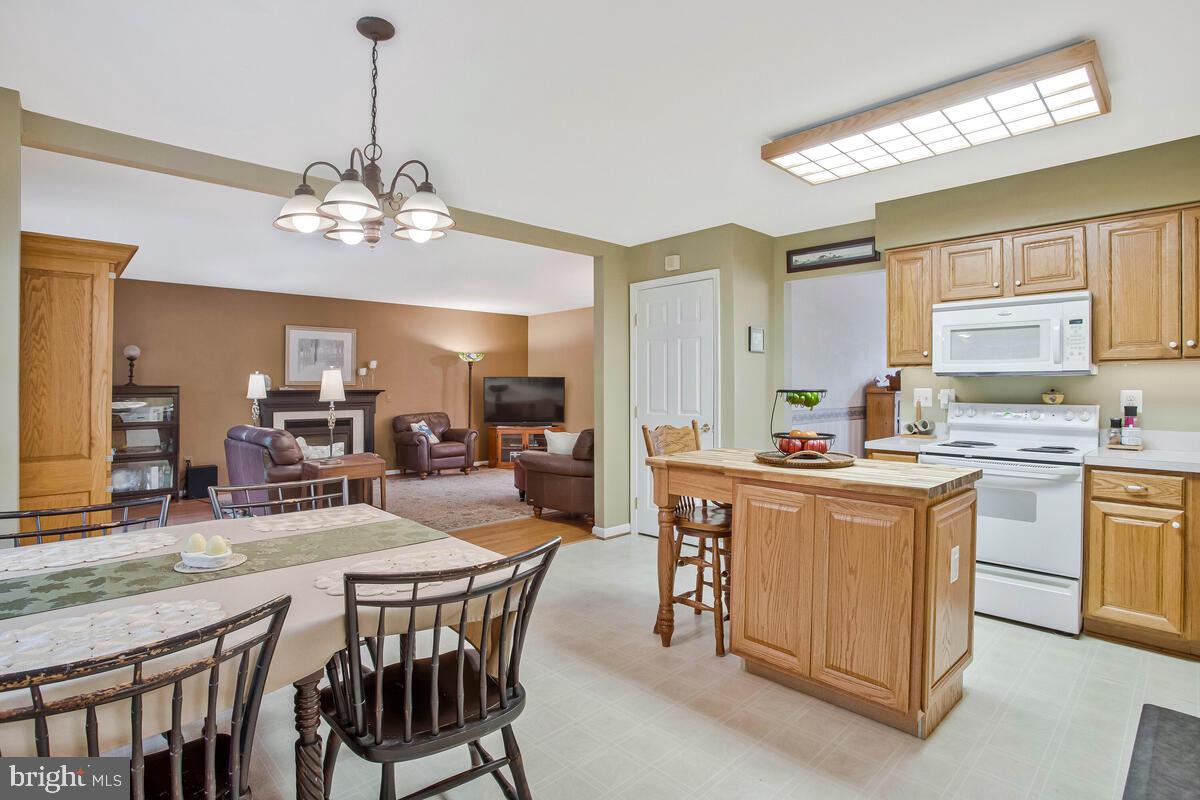1805 Rudolph Lane Lusby, MD 20657 - Photo 9 of 43 a kitchen with stainless steel appliances granite countertop a stove top oven a sink dishwasher a dining table and chairs with wooden floor