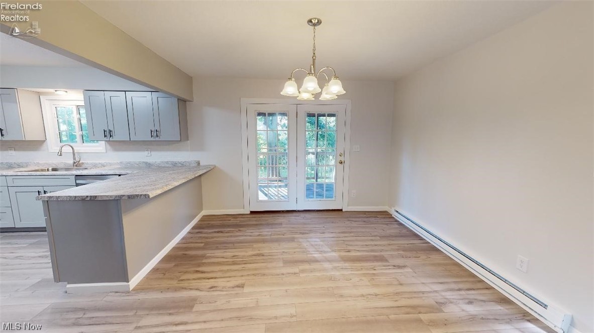 1715 Chenango Road Wakeman, OH 44889 - Photo 9 of 21 Kitchen featuring sink, light hardwood / wood-style flooring, pendant lighting, a baseboard radiator, and a notable chandelier