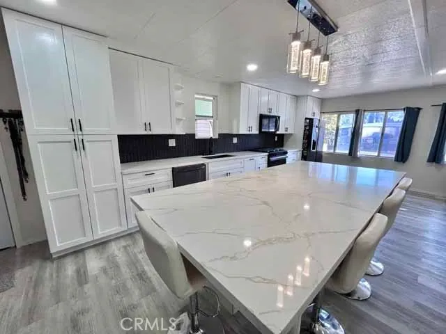 a view of kitchen island with stainless steel appliances refrigerator microwave and wooden floor