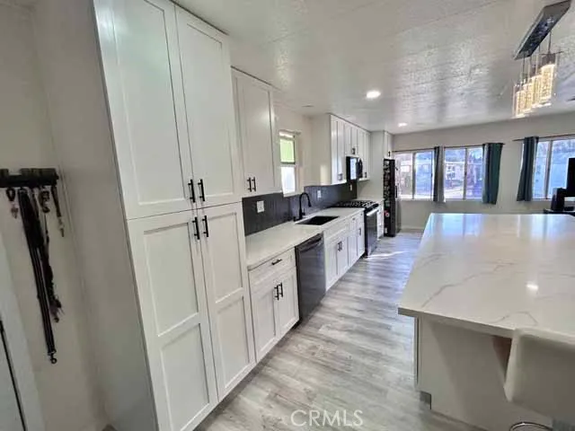 a large kitchen with stainless steel appliances a large counter top a stove a sink a refrigerator and cabinets