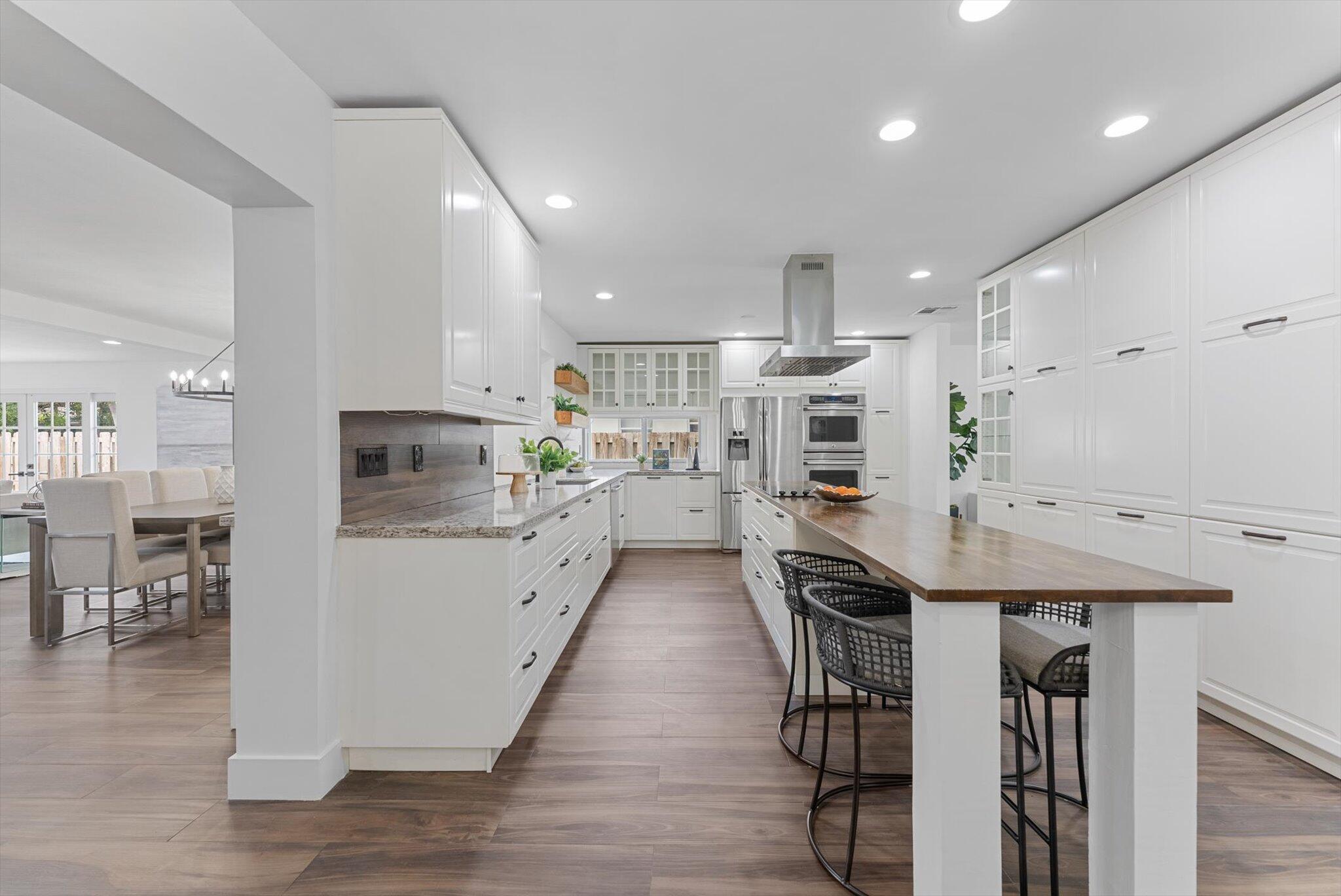 5412 Arthur Street Hollywood, FL 33021 - Photo 17 of 67 a kitchen with stainless steel appliances kitchen island granite countertop a refrigerator a stove a microwave oven a dining table and chairs with wooden floor