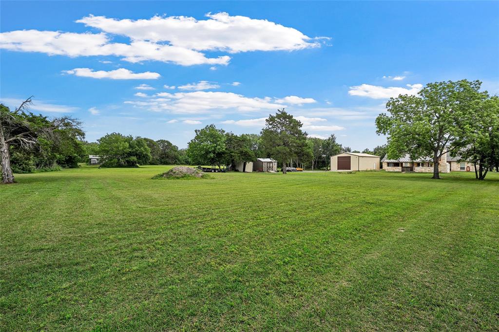 1117 Downsville Road Robinson, TX 76706 - Photo 31 of 40 Expansive grassy grounds featuring mature trees and a substantial outbuilding with a roll-up door