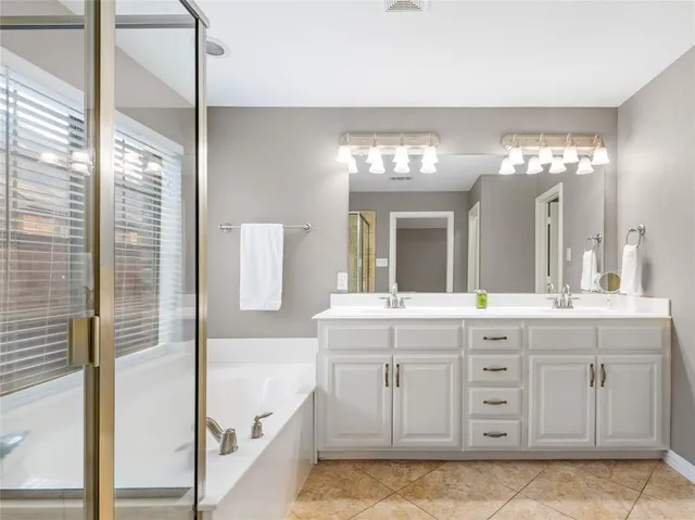 a spacious bathroom with a granite countertop sink a mirror a shower and a bathtub