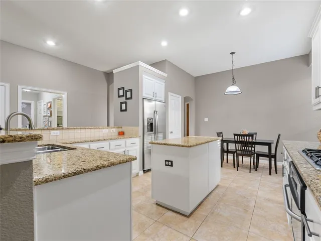 a large kitchen with kitchen island a sink a stove a dining table and chairs