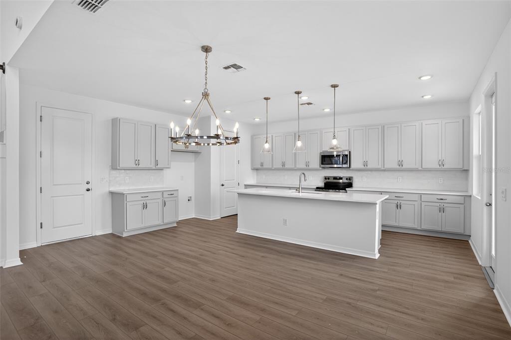 5788 Haystack Drive St. Cloud, FL 34771 - Photo 12 of 31 a large white kitchen with kitchen island a sink white cabinets and stainless steel appliances