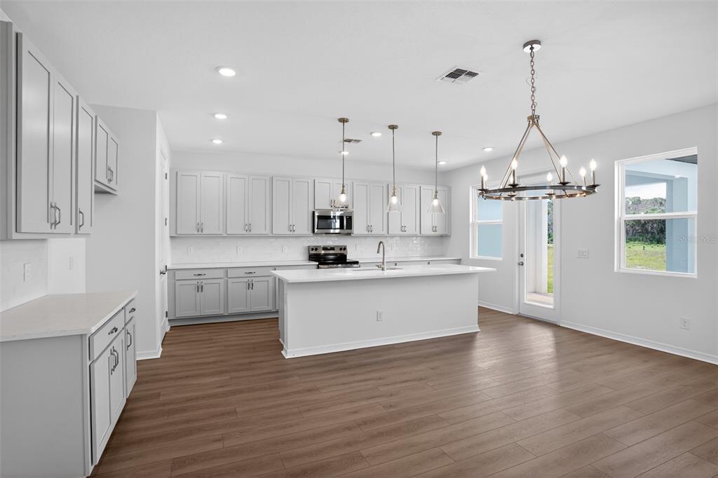 5788 Haystack Drive St. Cloud, FL 34771 - Photo 13 of 31 a large kitchen with white cabinets stainless steel appliances a sink and a stove