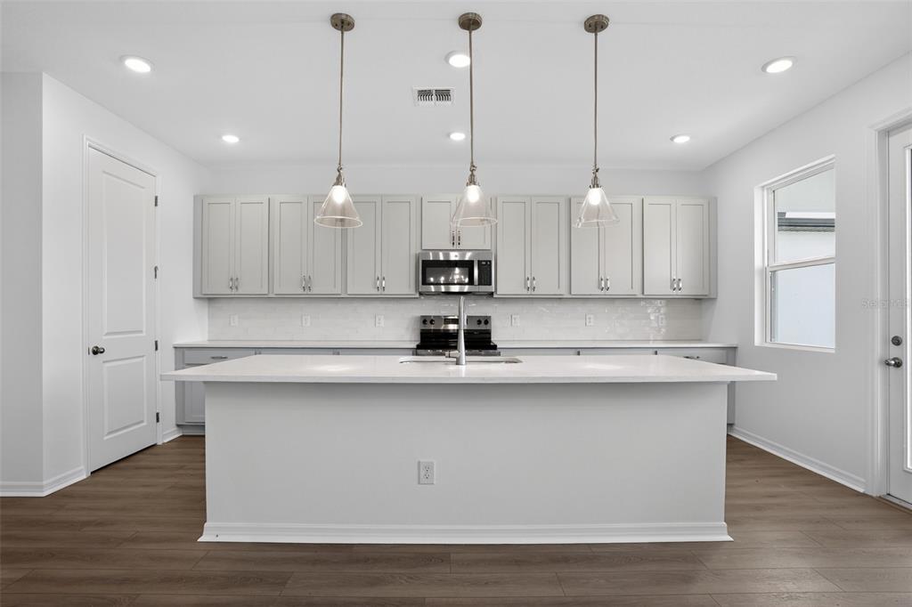 5788 Haystack Drive St. Cloud, FL 34771 - Photo 14 of 31 a view of a kitchen with kitchen island stainless steel appliances sink and wooden floor