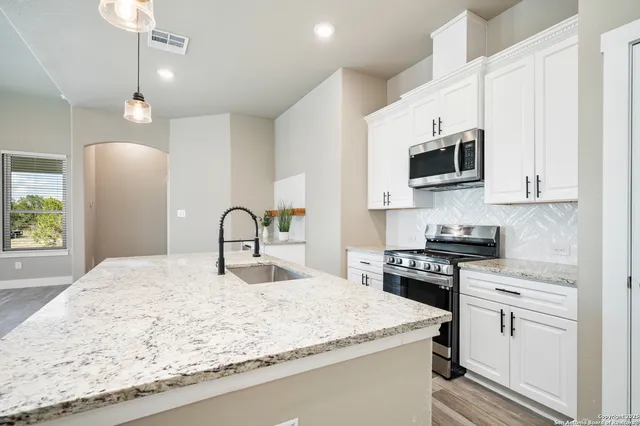 a kitchen with granite countertop white cabinets and stainless steel appliances