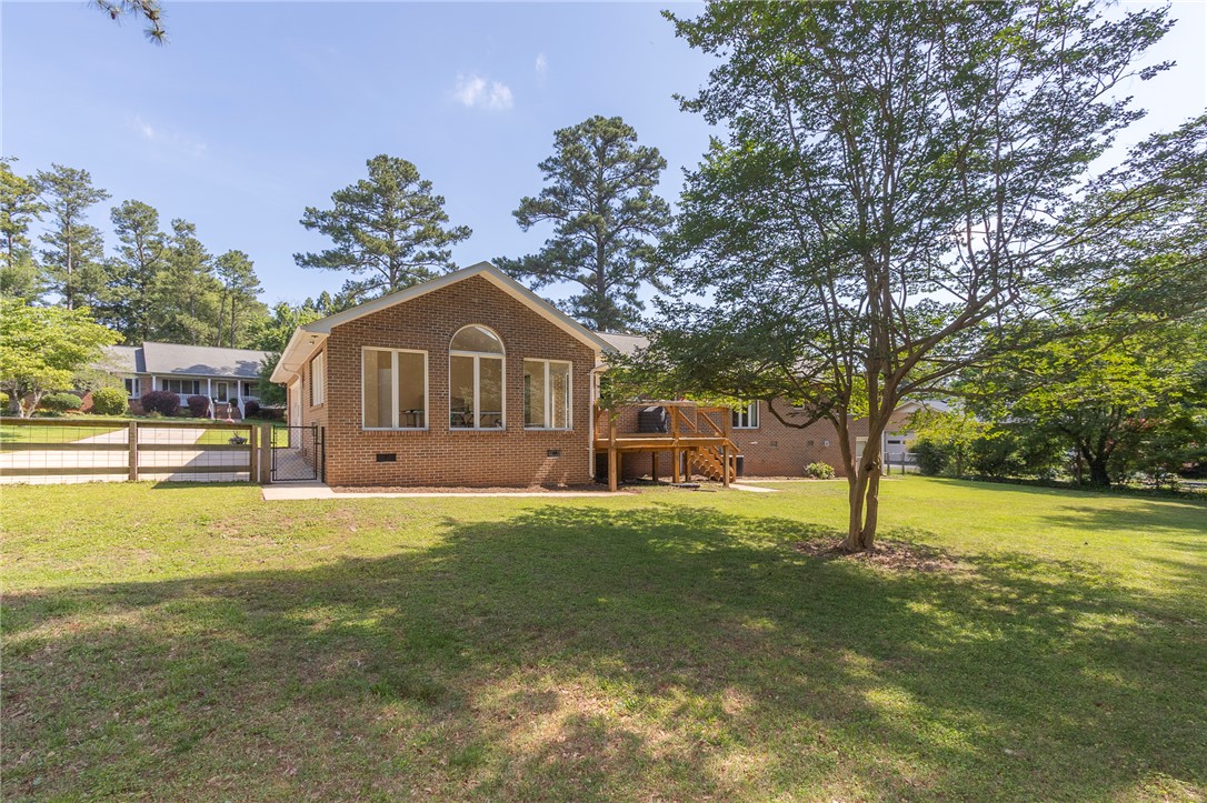 207 Laurel Ridge Road Anderson, SC 29621 - Photo 47 of 50 A spacious backyard with mature trees and a charming brick home featuring a deck and fenced area.