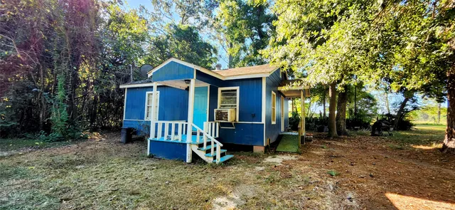 a view of a house with a yard and large trees