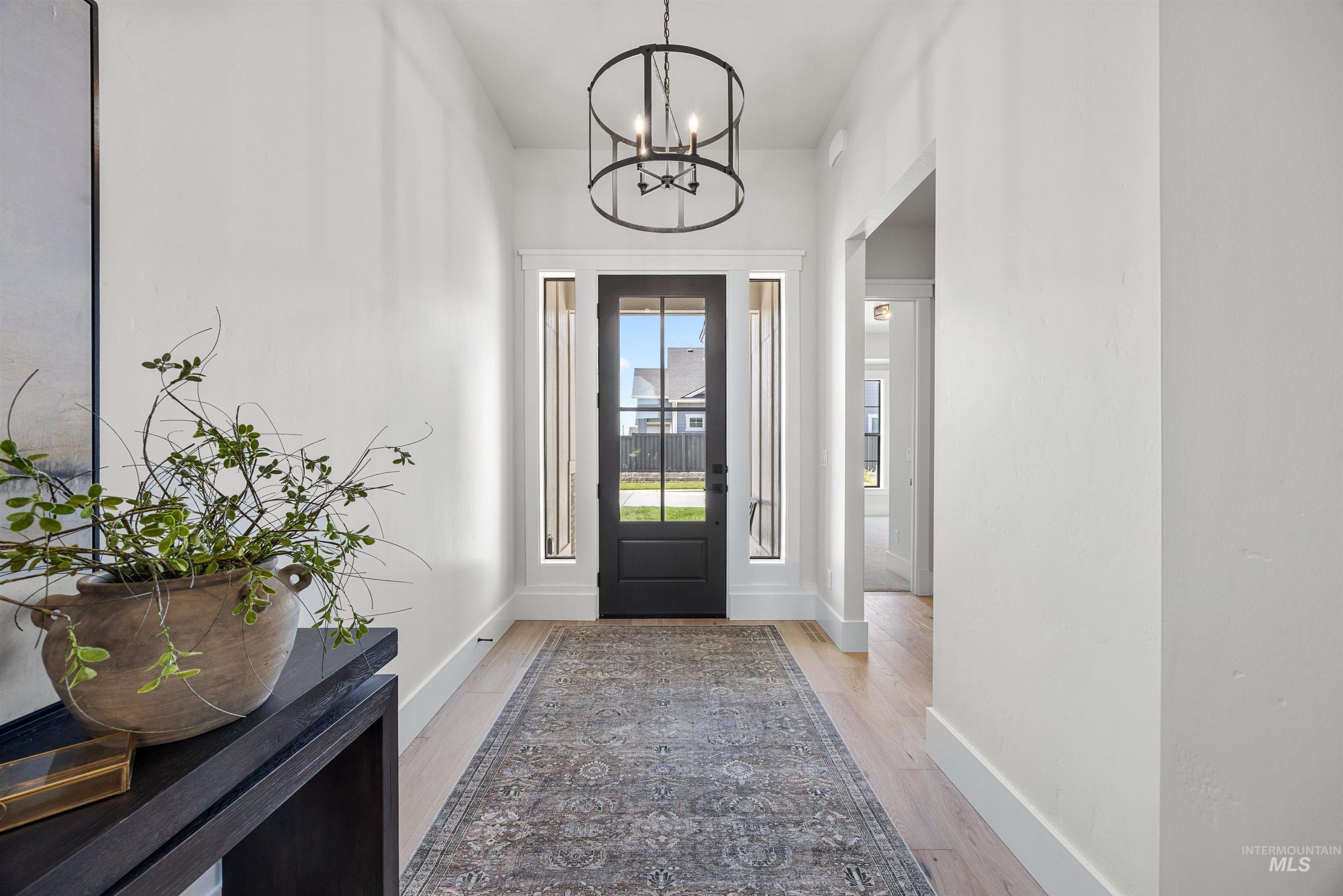 Entryway featuring wood-finish flooring, a black-framed glass door, and an overhead drum pendant light