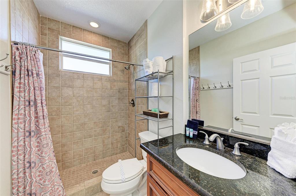 201 57th Street Holmes Beach, FL 34217 - Photo 17 of 48 a bathroom with a granite countertop sink toilet a mirror and shower