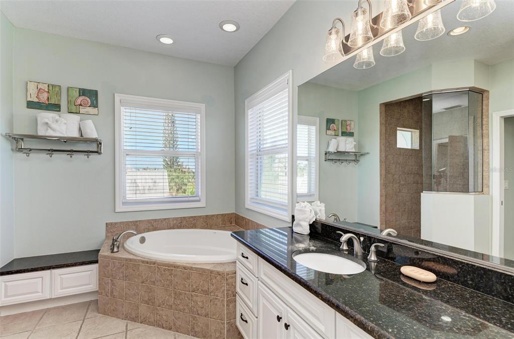 201 57th Street Holmes Beach, FL 34217 - Photo 27 of 48 a bathroom with a granite countertop sink a bathtub a mirror and shower