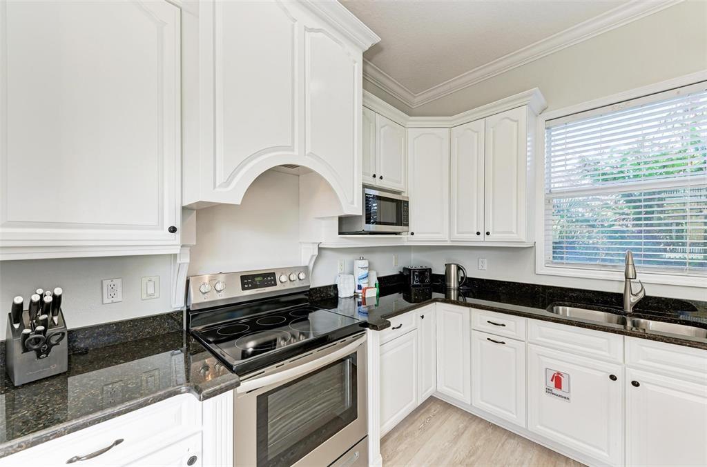 201 57th Street Holmes Beach, FL 34217 - Photo 7 of 48 a kitchen with granite countertop a stove a sink and white cabinets