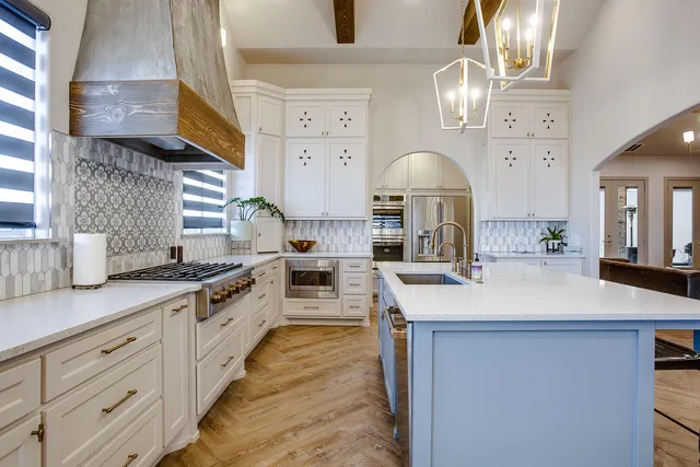 a large kitchen with stainless steel appliances granite countertop a sink dishwasher a stove and a dining table with wooden floor