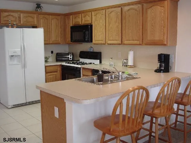 a kitchen with stainless steel appliances granite countertop a stove a refrigerator a sink a dining table and chairs