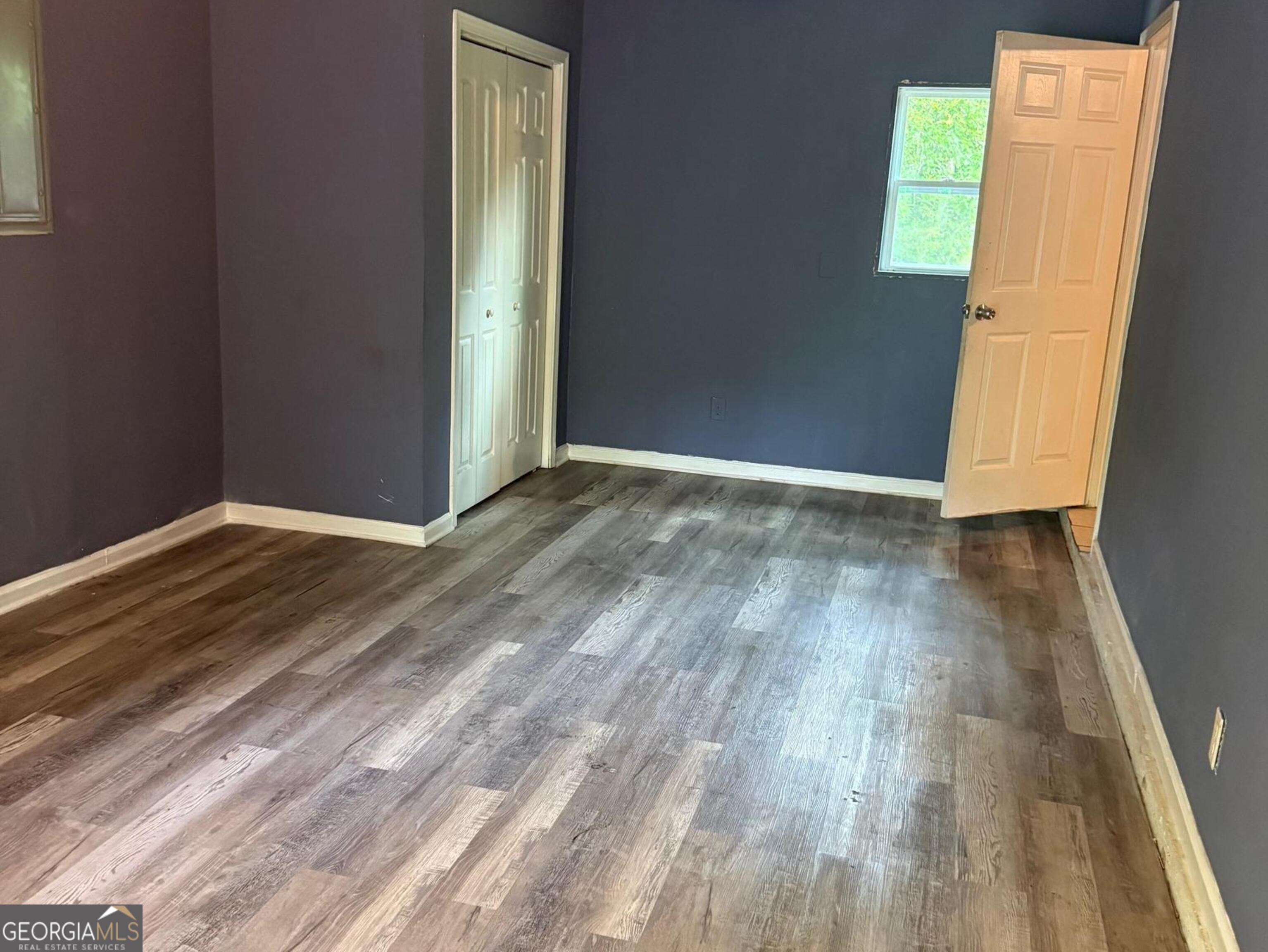 7055 Swift Street Lithonia, GA 30058 - Photo 2 of 9 an empty room with wooden floor and entrance
