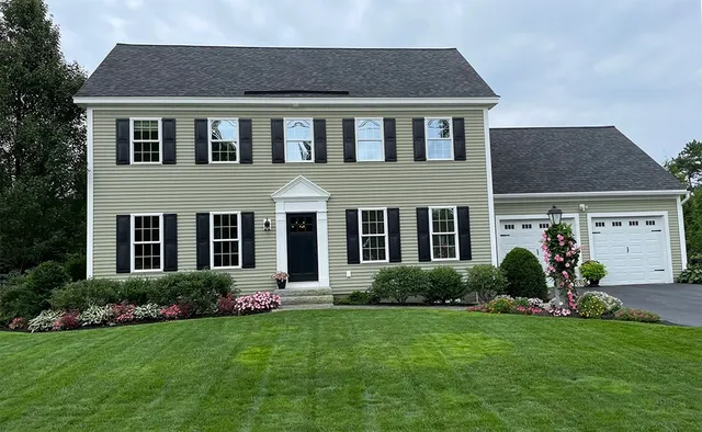 a brick house with a yard potted plants and a table and chairs