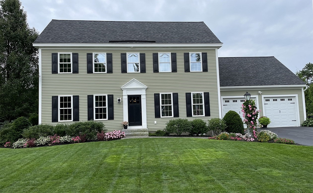 a brick house with a yard potted plants and a table and chairs