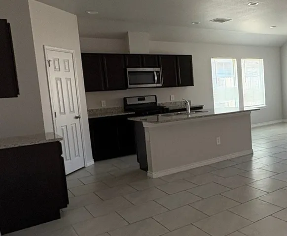 a kitchen with granite countertop a refrigerator and a stove top oven