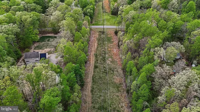 an aerial view of residential house with outdoor space and trees all around