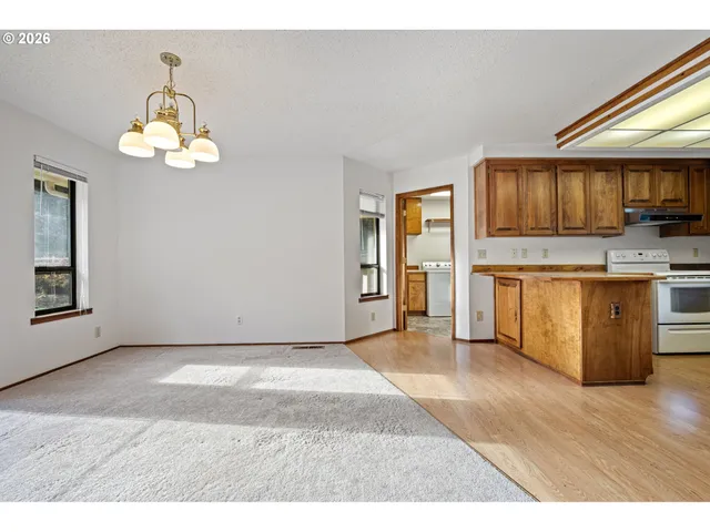 a view of a kitchen with wooden floor a sink a refrigerator and window