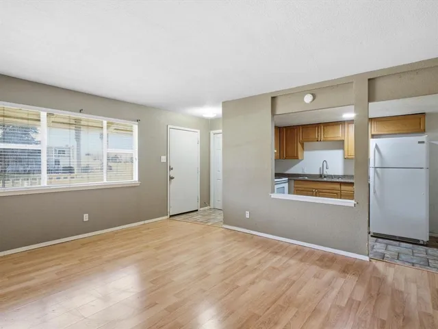 a view of an empty room with a window and a kitchen
