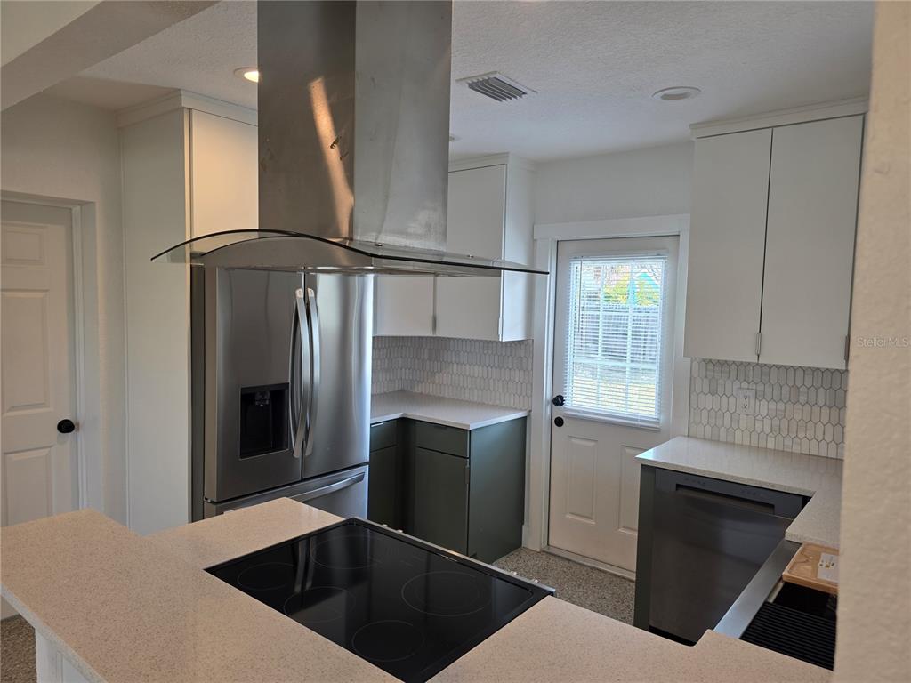 430 80th Way St. Pete Beach, FL 33706 - Photo 10 of 42 a kitchen with stainless steel appliances kitchen island granite countertop a refrigerator a stove and a sink with wooden floor