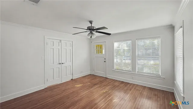 a view of an empty room with wooden floor and a window