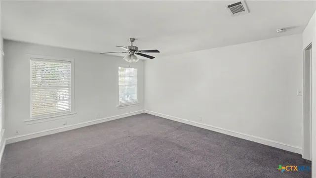 an empty room with windows and fan