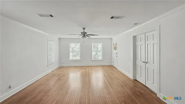 a view of an empty room with wooden floor and a window