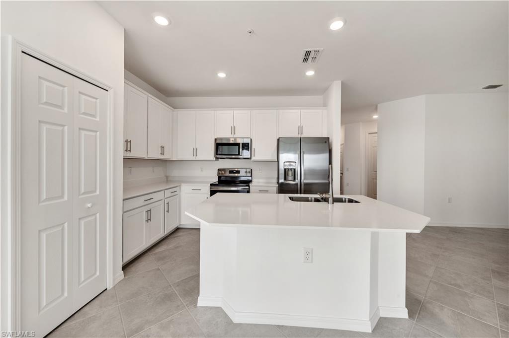 43997 Boardwalk Loop, Unit 1838 Punta Gorda, FL 33982 - Photo 12 of 45 a large kitchen with kitchen island a stove a sink a refrigerator and a refrigerator