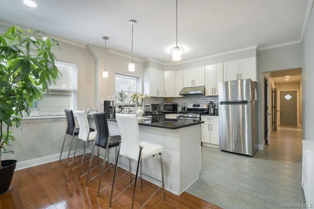 a kitchen with stainless steel appliances kitchen island granite countertop a refrigerator a stove a sink a dining table and chairs with wooden floor