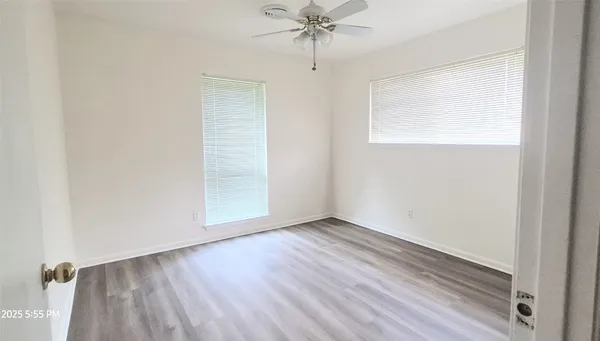 an empty room with wooden floor closet and windows