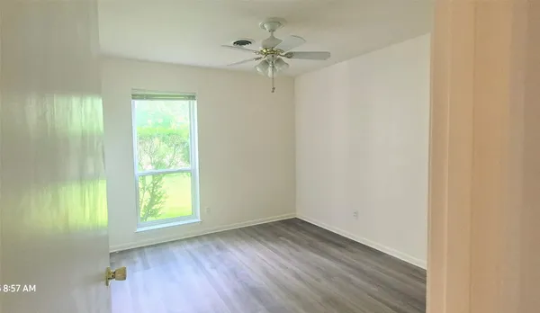 an empty room with a window and a fan