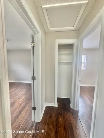 a view of an empty room with window and wooden floor