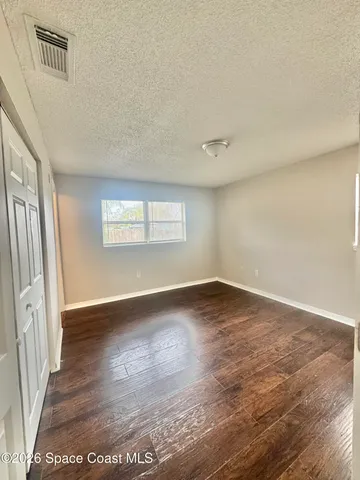a view of an empty room with window and wooden floor