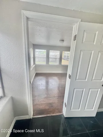 a view of empty room with wooden floor and fan