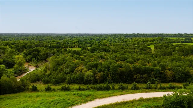 an aerial view of residential house with outdoor space and trees all around
