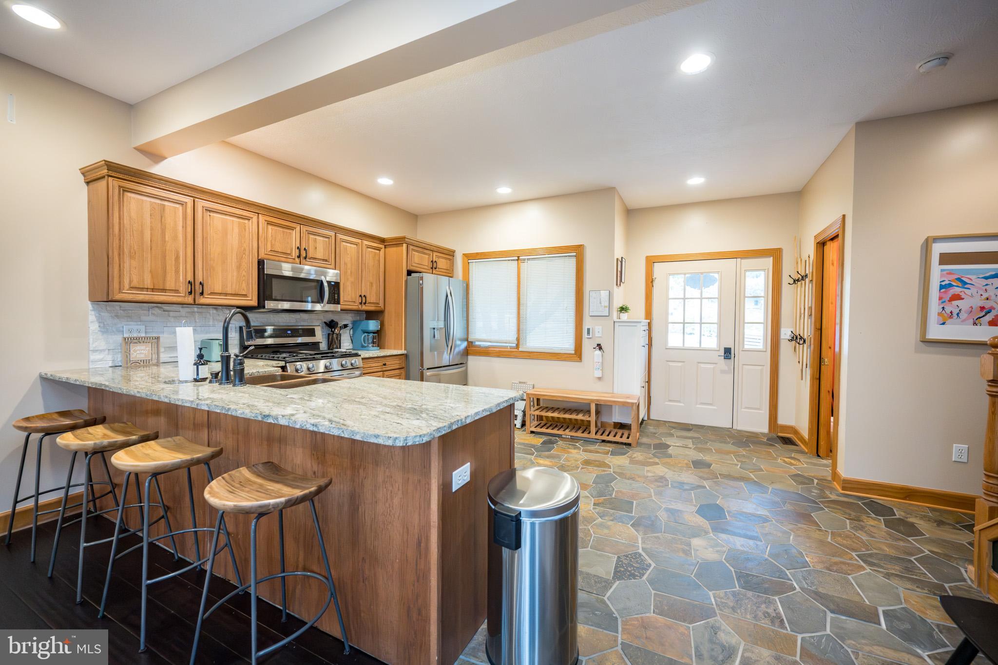 147 Marsh Hill Road McHenry, MD 21541 - Photo 10 of 60 a kitchen with stainless steel appliances granite countertop a stove top oven a sink dishwasher and a refrigerator with wooden cabinets
