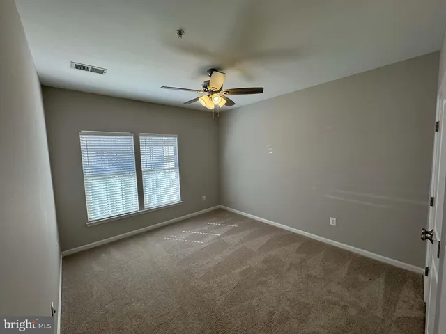 an empty room with chandelier fan and windows