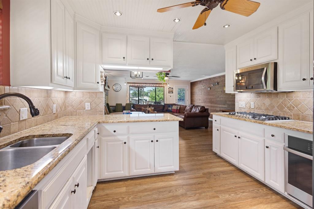 227 Scenic Road Trinidad, TX 75163 - Photo 7 of 40 a kitchen with a sink dishwasher and white cabinets with wooden floor