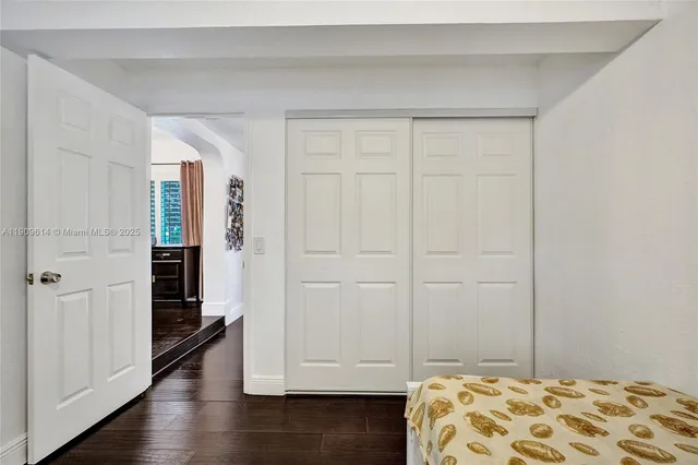 a bedroom with a bed and dresser with wooden floor